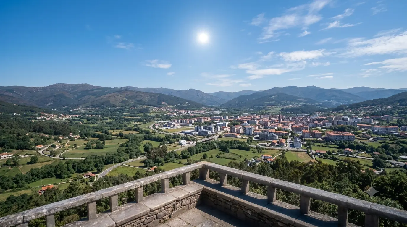 Vista de um miradouro sobre o vale e a cidade, com o Sol ainda pleno num céu azul.