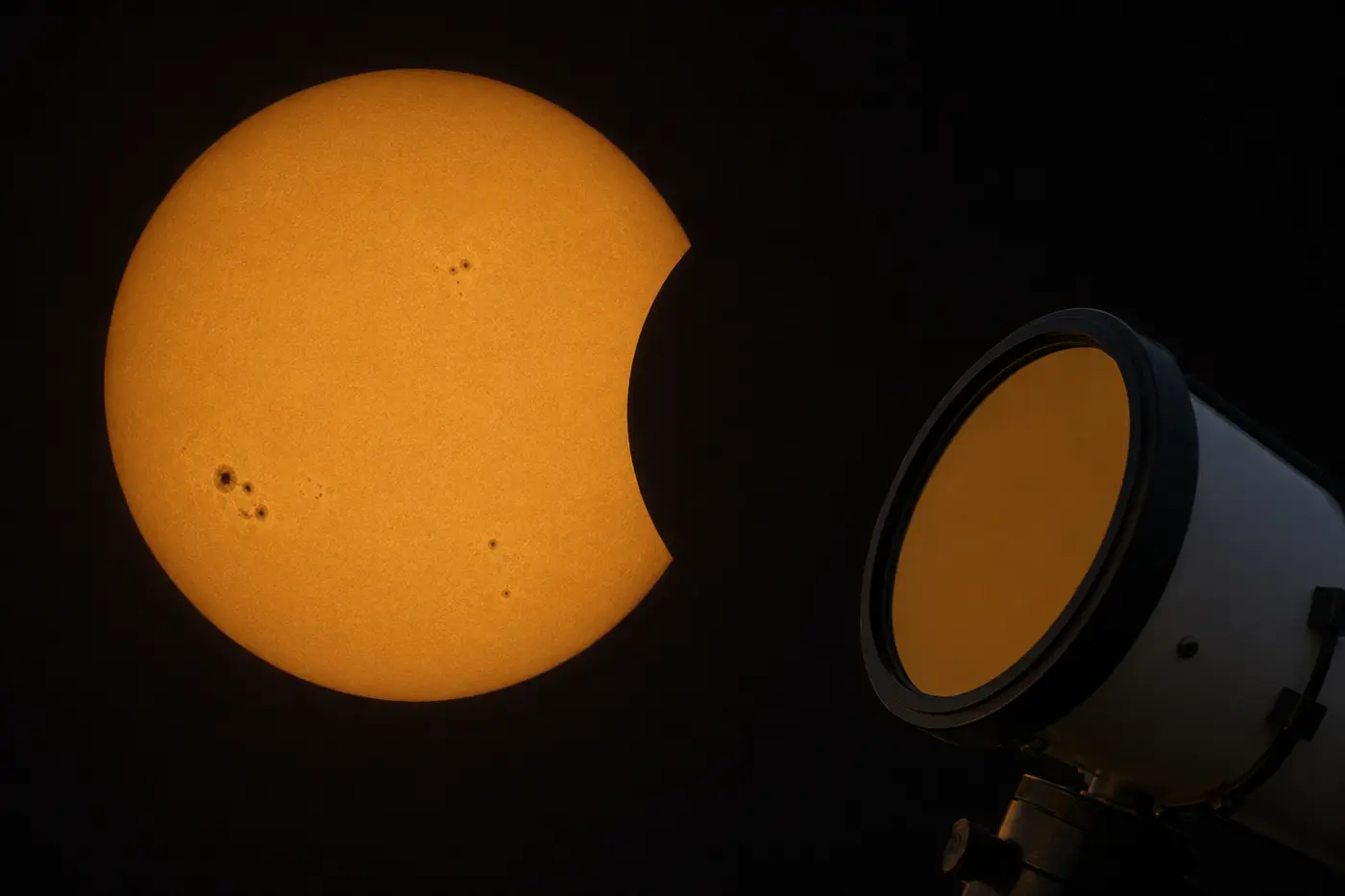 O Sol com manchas solares e a primeira “dentada” da Lua, visto com filtro solar junto a um telescópio.