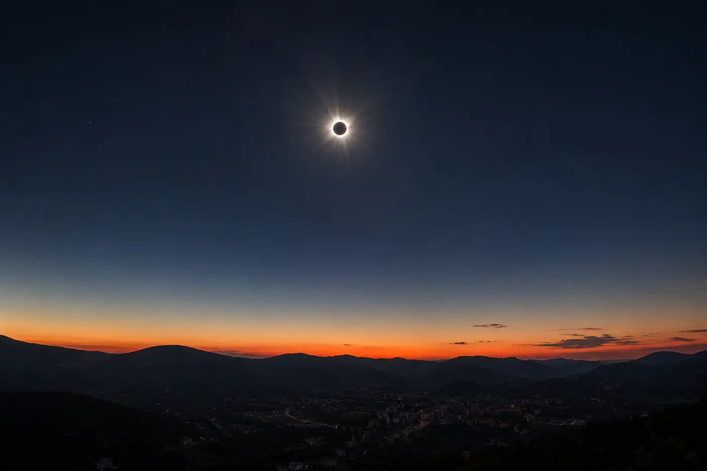 O Sol totalmente eclipsado no céu escuro, com o horizonte alaranjado em todas as direções.